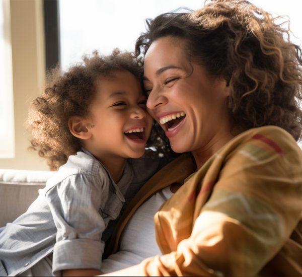 Attractive woman and little girl sitting on comfortable couch at home. Young mother talking communicates with small adorable daughter. Best friends happy motherhood weekend together with kid concept laughing and embracing